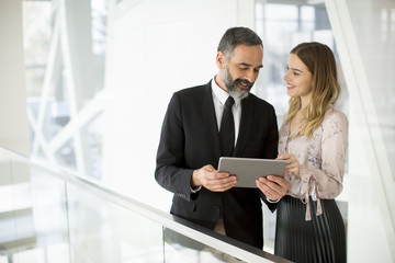 Young businesswoman and businessman look on digital tablet and discuss aout project