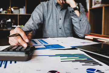 Close up view of bookkeeper , Male using calculator and laptop computer  to audit finance at...