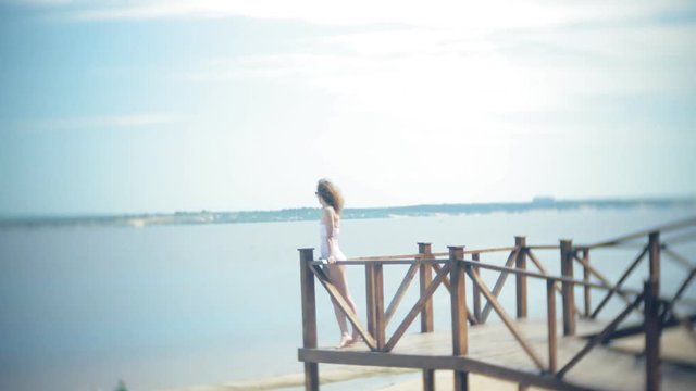 Hot girl standing on the beach on the bridge in the sun. 4k.