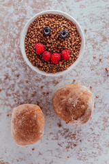 Smile from blackberries and raspberries in a plate with buckwheat and rolls.