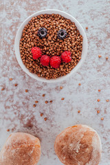 Smile from blackberries and raspberries in a plate with buckwheat and rolls.