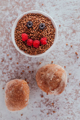 Smile from blackberries and raspberries in a plate with buckwheat and rolls.