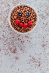 Smile from blackberries and raspberries in a plate with buckwheat and rolls.