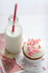 Sweet food composition with creamy cupcake with rose chocolate decoration and a bottle with fresh milk cocktail 