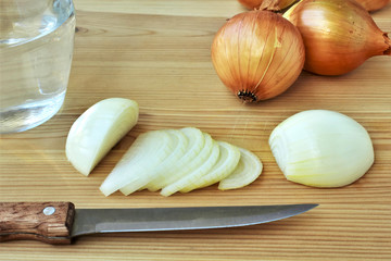 Chopped fresh onion, knife and jar with water for stinging a knife during cutting.