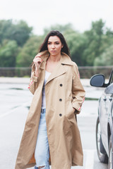 Beautiful woman in the beige coat and jeans on the street