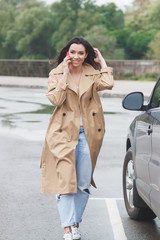 Beautiful woman in the beige coat and jeans on the street