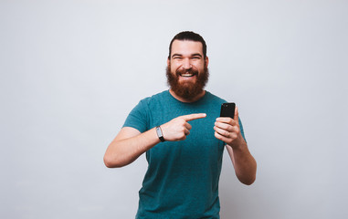 Happy bearded hipster man pointing at phone