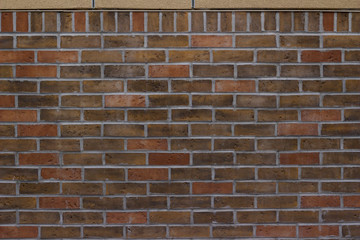 Brick wall background with earth tone color bricks in traditional pattern with top row header
