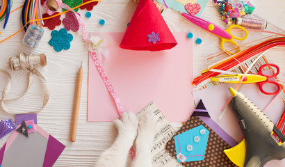 Top view of table with elements for scrapbooking, tools for decoration and handmade albums and hands of master.