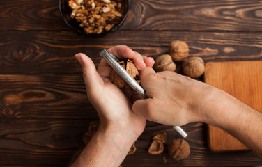 Freshly cracked walnut in nutcracker with whole walnuts on wood background. Macro with shallow dof.