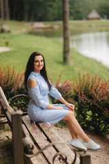 Obraz premium Lady in blue dress sitting on the bench near the lake
