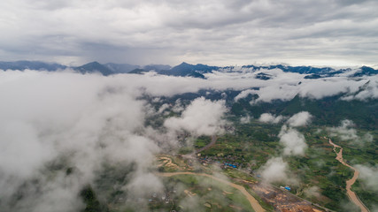 aerial view of cloudscape above farmland, river and roll of hills