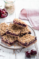 Homemade crumbled oatmeal and berry bars on light rustic background