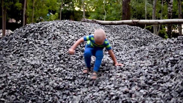 A little boy is climbing a pile of rubble.