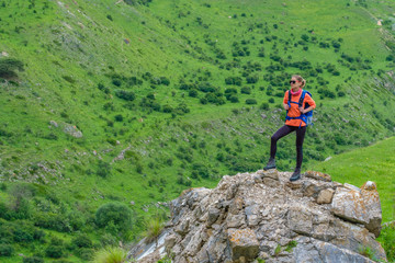 Young woman standing with a backpack in a mountain valley.	