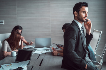 businessman using smart phone at meeting room with his colleagues background. 