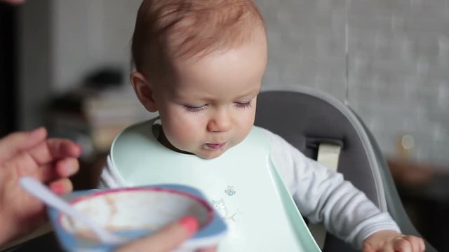 Mother feeding baby boy in high chair, close up