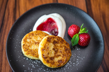 Cottage cheese pancakes. Russian syrniki with cranberry jam and yogurt, selective focus