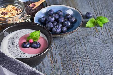 Yogurt with muesli and blueberries with mint, healthy dessert on wood