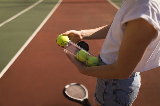 Woman removing tennis ball from tennis ball case