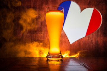 Creative concept. Pint of fresh beer on table with blurred flag of France on background or Glass of lager beer ready for drink. Copy space.