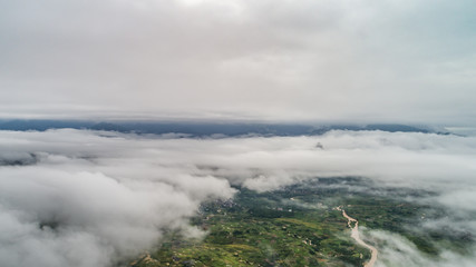 aerial view of cloudscape above village, farmland and roll of hills in morning