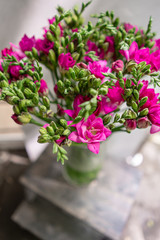 Obraz na płótnie Canvas bright pink freesia flowers in glass vase on wooden table. Beautiful summer bouquet. Arrangement with mix flowers. The concept of a flower shop. Content for the catalog