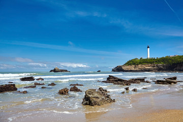 Biarritz, France. Sand beach Miramar Plage overlooking the white lighthouse - Phare de Biarritz on the Pointe Saint-Martin.  Bay of Biscay, Atlantic coast, Basque country. Sunny summer day - obrazy, fototapety, plakaty