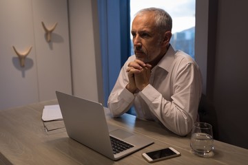 Businessman thinking deeply while sitting at desk