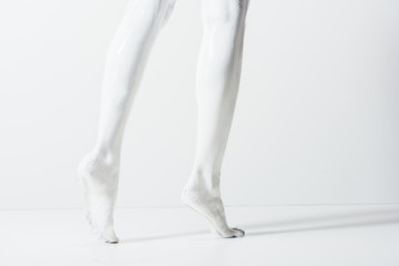 cropped image of girl with legs painted with white paint walking on white floor