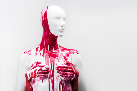 cropped image of woman in red paint touching mannequin breasts isolated on white