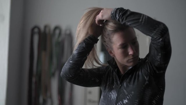 Crossfit girl getting ready for workout. making her hair.