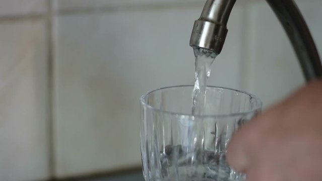 Pouring a glass with drinking water from kitchen tap