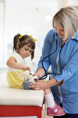 Obraz premium Doctor examining toy and little girl using stethoscope