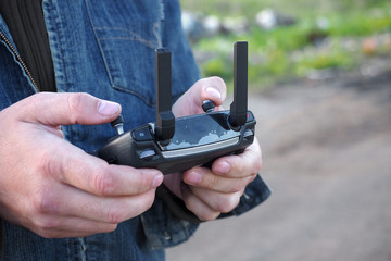 Male hands with remote control of quadrocopter, close up, front view