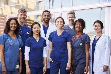Smiling medical team standing together outside a hospital - obrazy, fototapety, plakaty