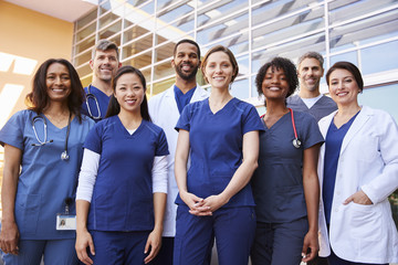 Smiling medical team standing together outside a hospital - obrazy, fototapety, plakaty