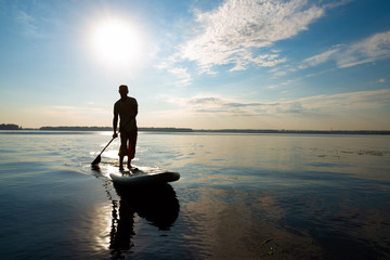 Silhouette of man, who is training on a SUP board