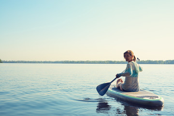Smiling female relaxing on a SUP board and enjoying life