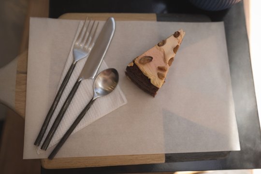 Pastry cake with spoon, fork and butter knife on wax paper