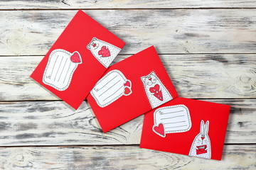Three red envelopes with a loving cat, mouse and bunny and with copy space for writing on a vintage background of white boards