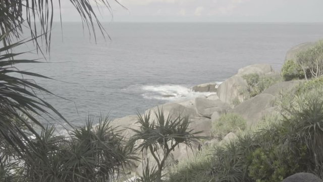 The sea wave with foam breaks about the rocky coast of the island. S-log, ungraded