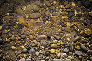 Natural concept background of clear river water and stone beach, outdoor day light
