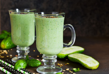 Green smoothies with avocado, cucumber, basil and granola on a dark stony background. Dietary drink.