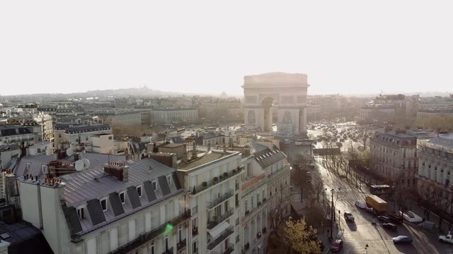 Sunny morning in Paris. A wide aerial shot shows the Arc de Triomphe and the Champs Elysees in golden morning light. The camera sinks into a small park in Avenue Foch.