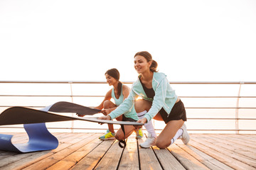Two sports women friends outdoors on the beach with carpet.