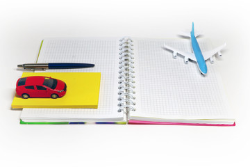 pen, airplane, car,  and notebook on a light background