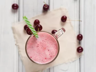 Foto op Plexiglas Milkshake Milkshake or cherry smoothie on white wooden table. Wholesome breakfast