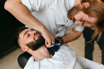 Barber Shaving Man Beard With Straight Razor In Barber Shop